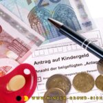 Auf einem Kindergeldantrag liegen ein Kugelschreiber, Geldscheine und Münzen.